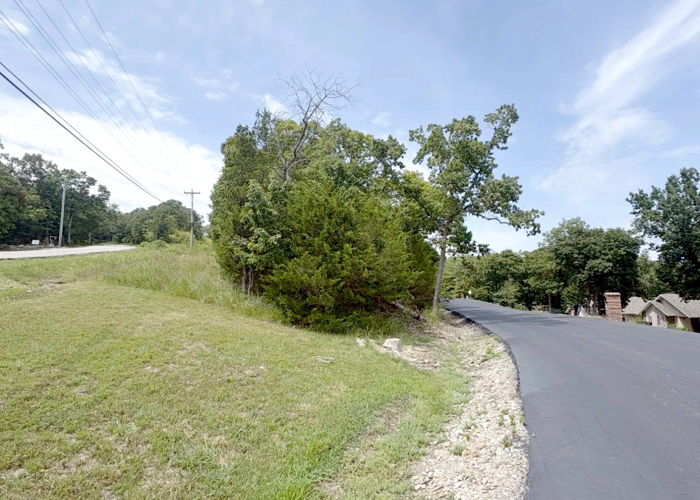 The same subdivision road frontage after the work: dead wood removed, shoulder and grass clear of debris