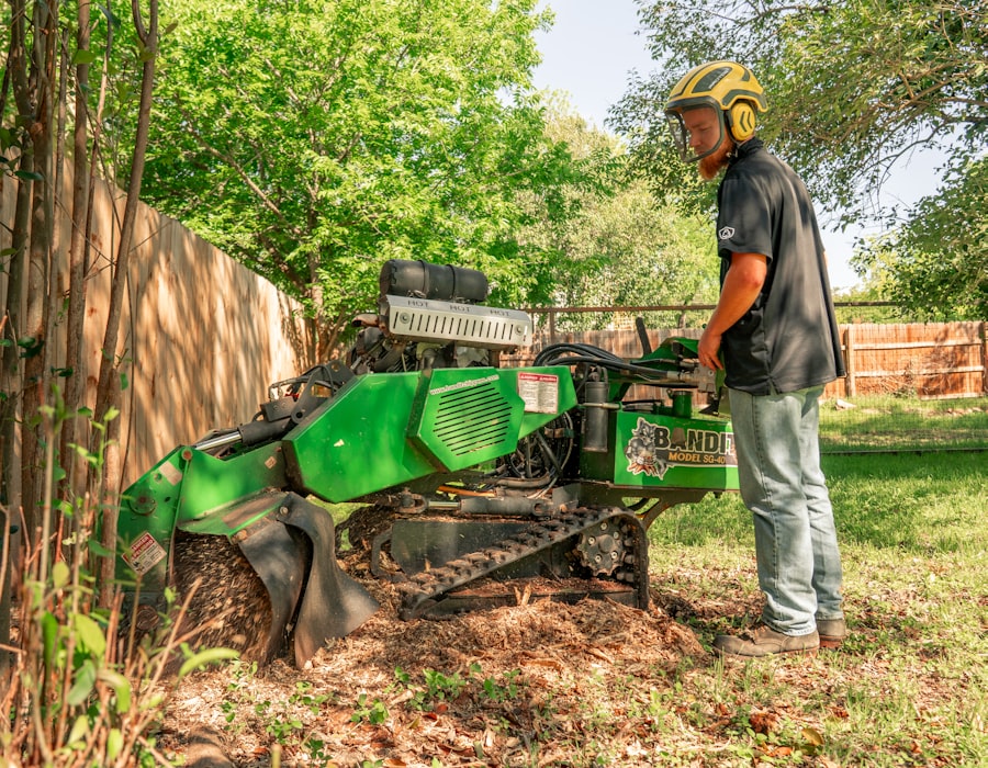 Operator running a tracked stump grinder in a fenced backyard