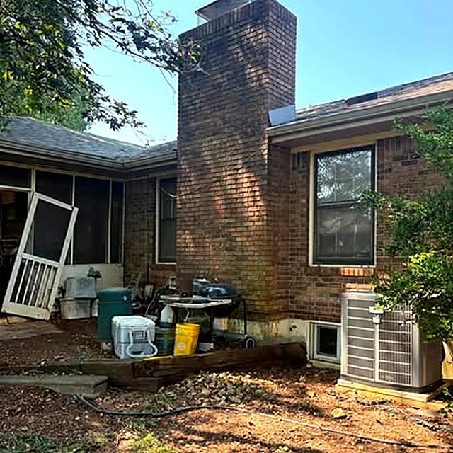 The same house after the work: the leaning tree is gone from the porch and chimney and the ground beneath is raked clear